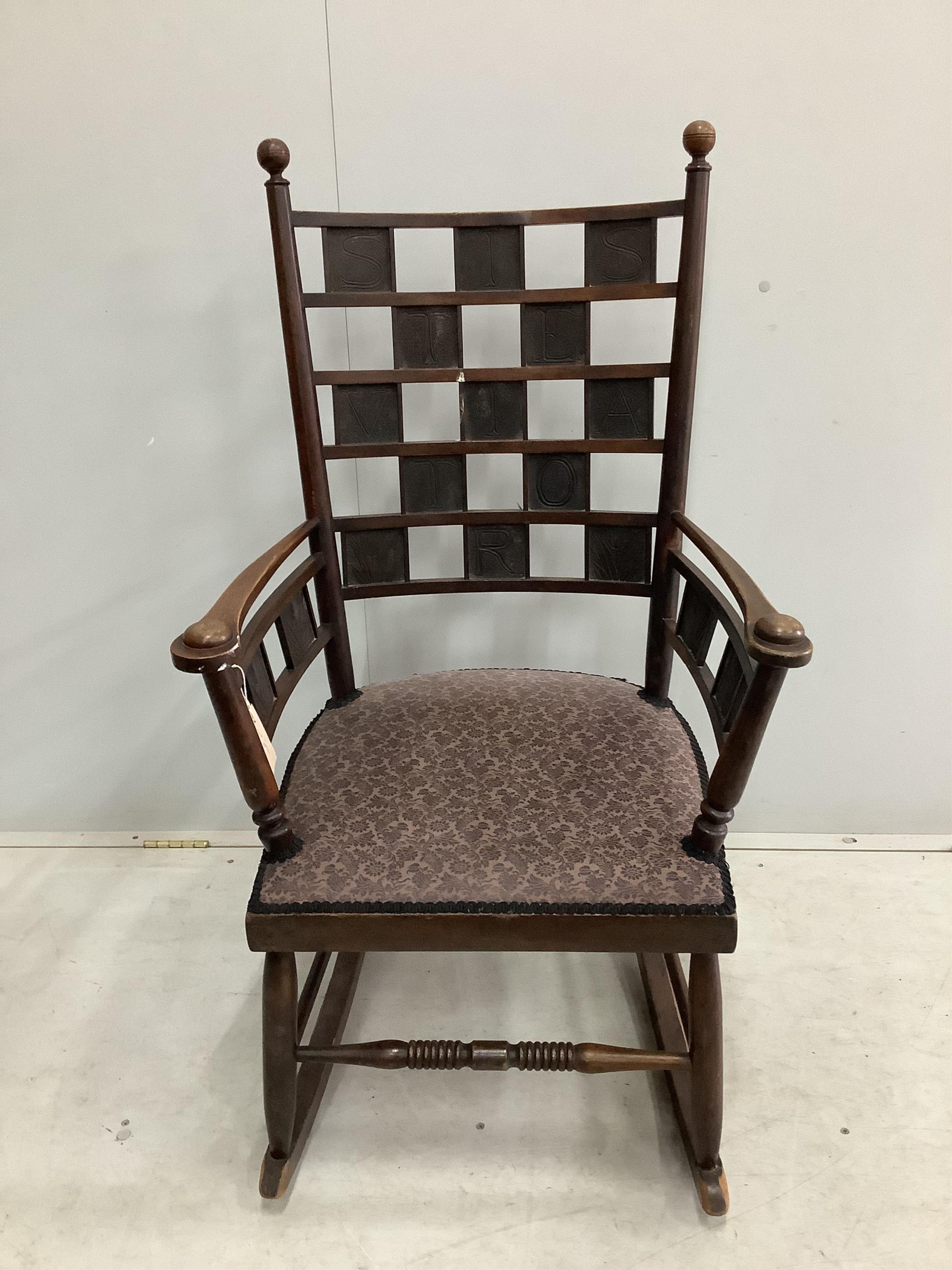 An Arts & Crafts mahogany rocking chair with copper panelled back inscribed 'Siste Viator' (stop, traveler - often used on Roman roadside tombs), width 60cm, depth 45cm, height 108cm. Condition - fair